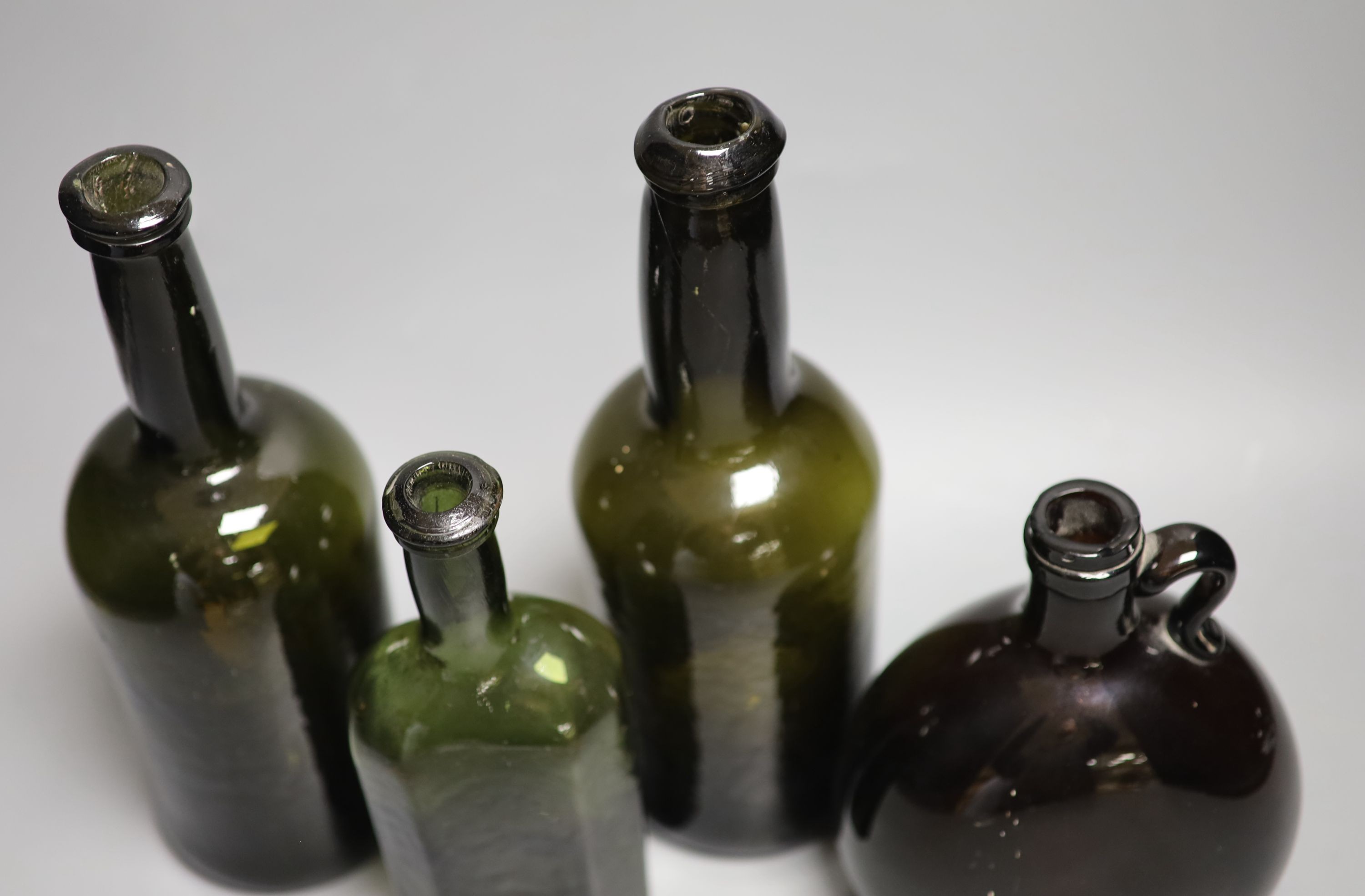 Two English dark green glass wine bottles, late 18th century, a Victorian amber glass hock jug and an early 19th century dark green glass small bottle, tallest 26.5cm (4)